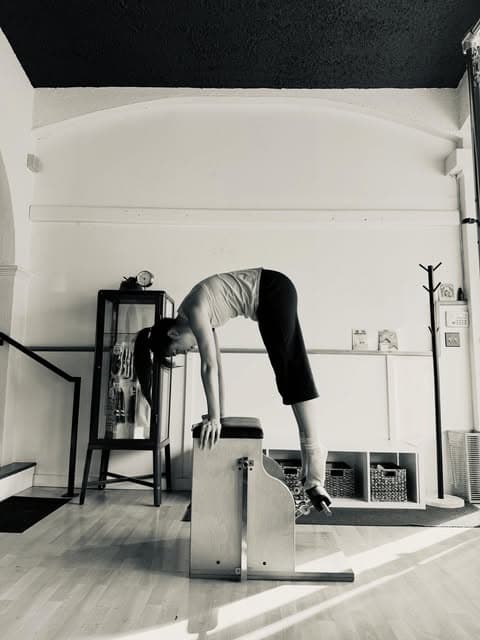 A client working through a long back stretch over the high chair at New Classic Pilates